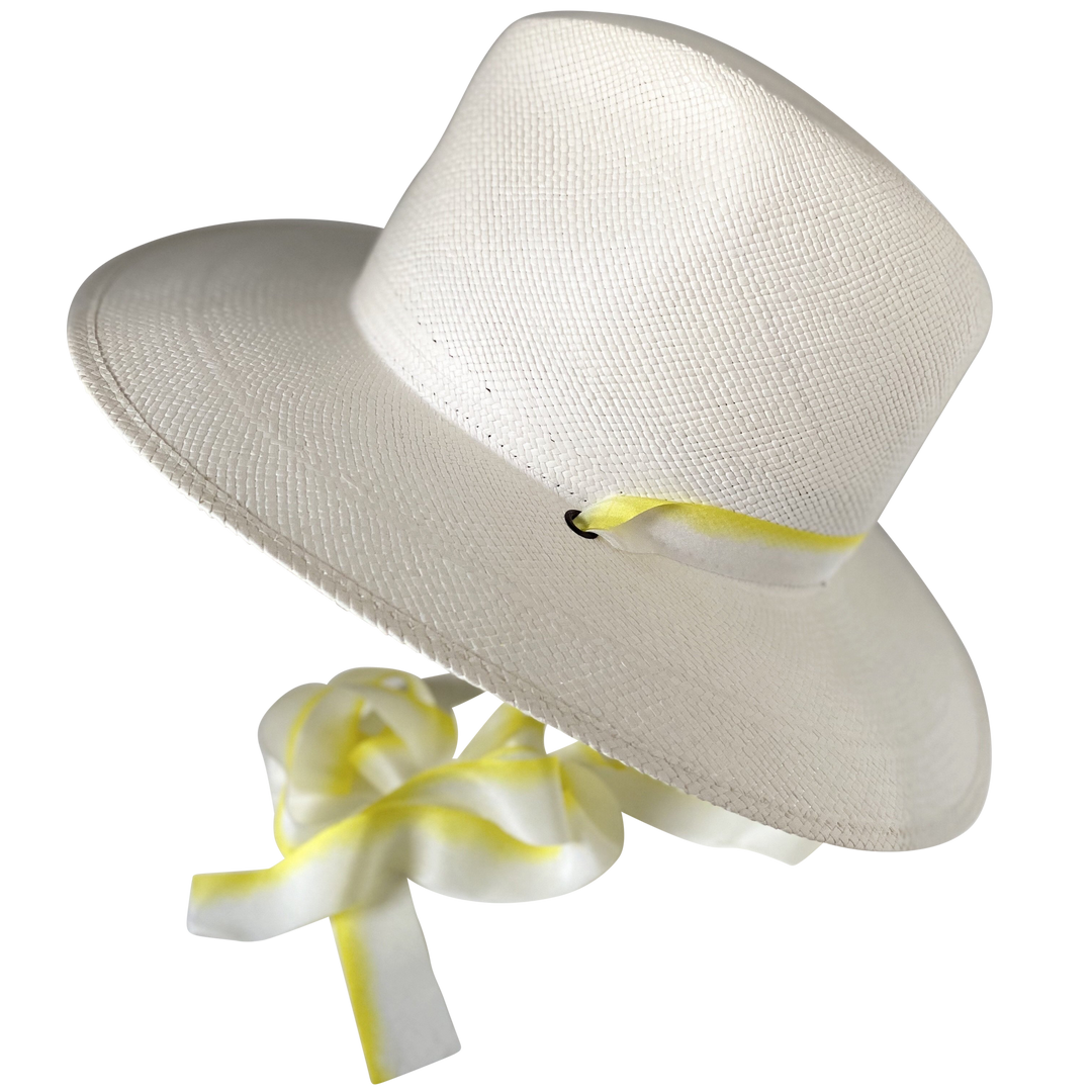 The Siena white toquilla straw wide-brim hat with yellow and white silk drop-down ribbon, angled product cutout with ribbon detail
