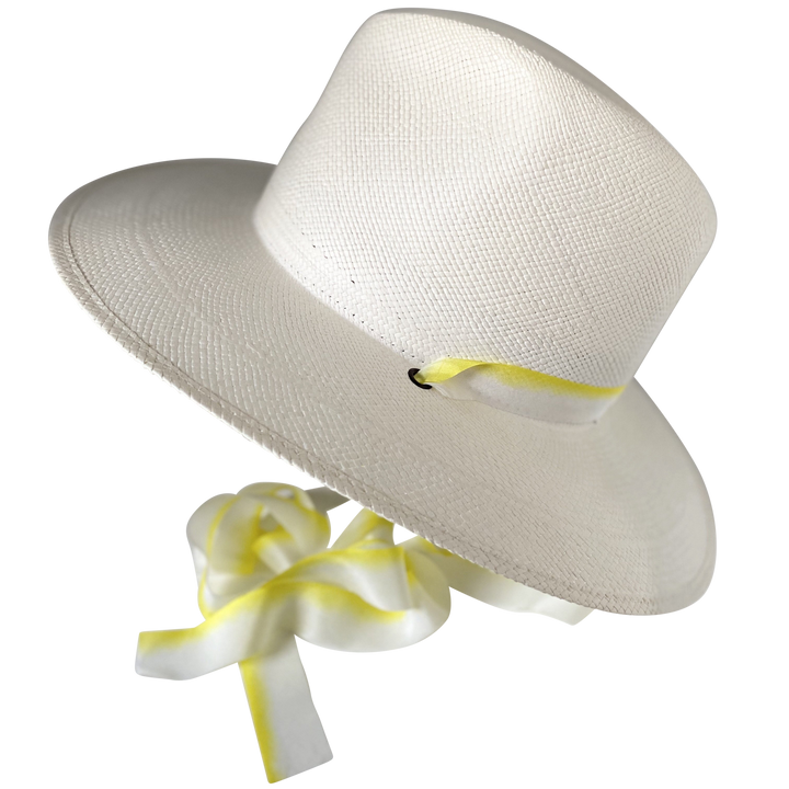 The Siena white toquilla straw wide-brim hat with yellow and white silk drop-down ribbon, angled product cutout with ribbon detail