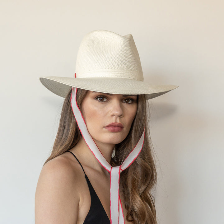 Khia Tullae The Morgan white toquilla straw wide-brim hat with red and white drop-down silk ribbon tied under chin, front view on model