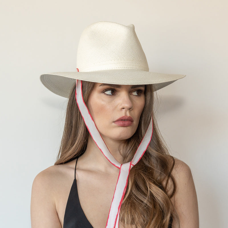 Khia Tullae The Morgan white toquilla straw wide-brim hat with red and white drop-down silk ribbon tied under chin, side view on model