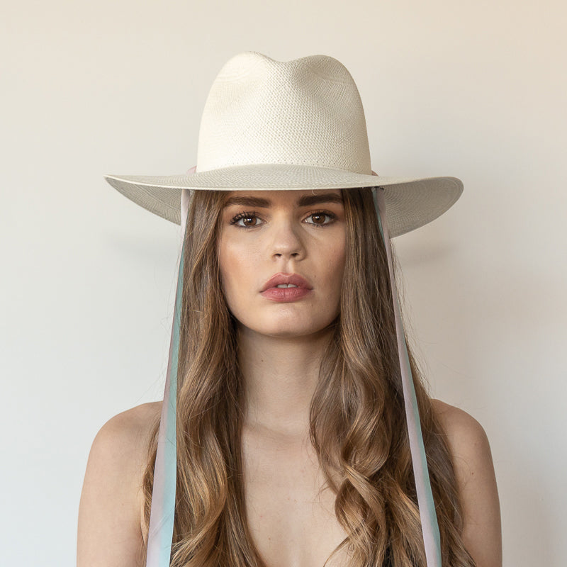 Khia Tullae The Audrey white toquilla straw wide-brim hat with pastel blue and pink drop-down silk ribbon ties, front view on model