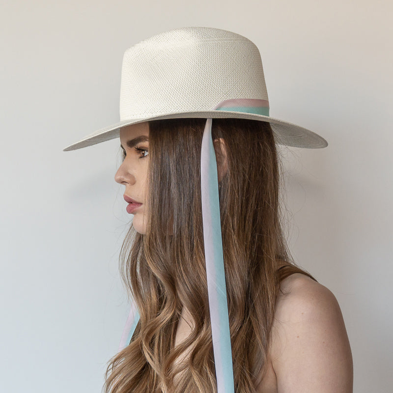Khia Tullae The Audrey white toquilla straw wide-brim hat with pastel blue and pink drop-down silk ribbon ties, side view on model