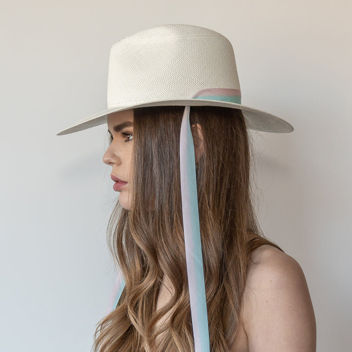 Khia Tullae The Audrey white toquilla straw wide-brim hat with pastel blue and pink drop-down silk ribbon ties, side view on model