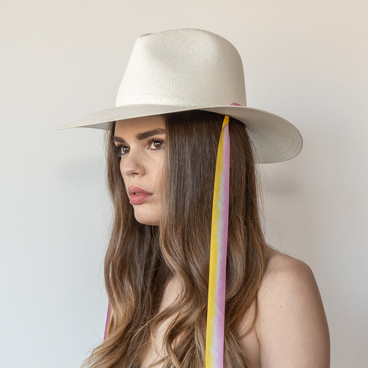 Khia Tullae The Bailey white toquilla straw wide-brim hat with yellow and pink drop-down silk ribbon ties, side view on model