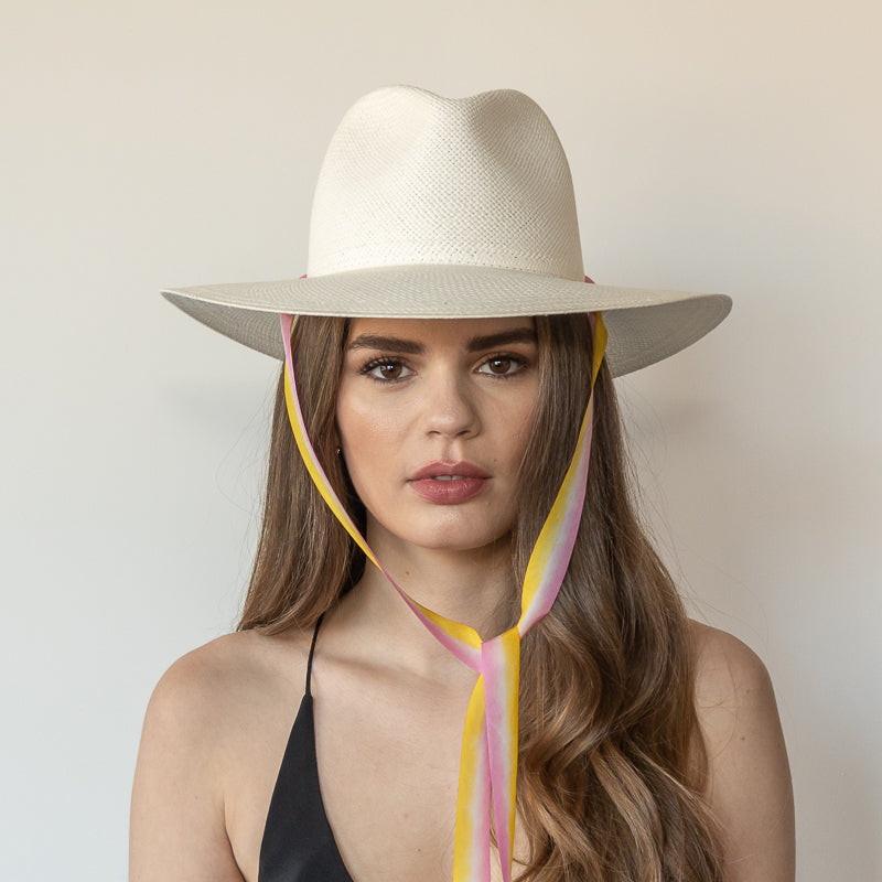 The Bailey white toquilla straw wide-brim hat with yellow and pink drop-down silk ribbon tied under chin, front view on model