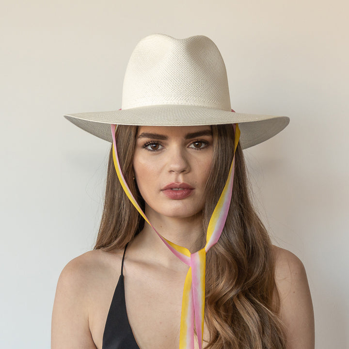 The Bailey white toquilla straw wide-brim hat with yellow and pink drop-down silk ribbon tied under chin, front view on model