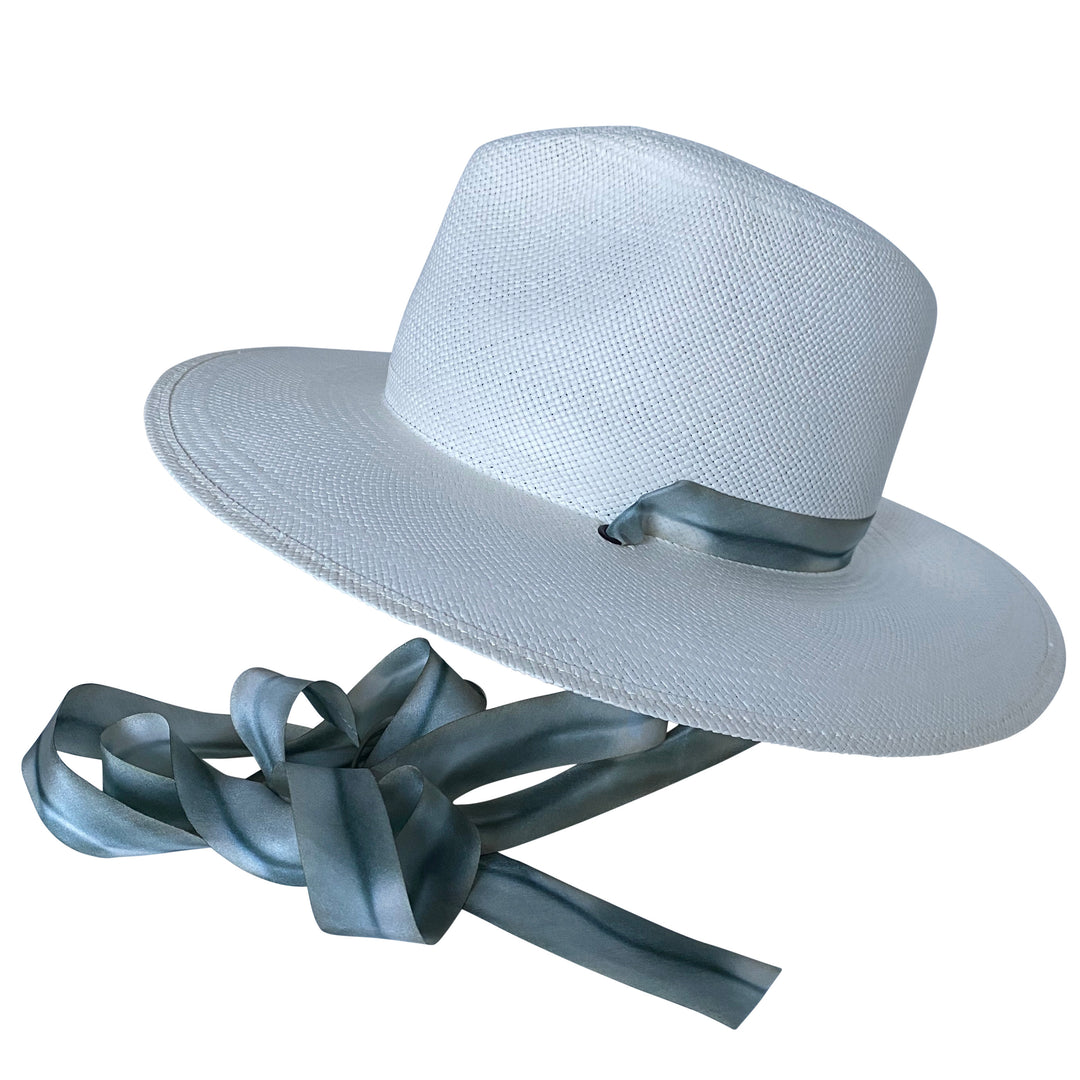 The Bexley white toquilla straw wide-brim hat with blue-grey silk drop-down ribbon, angled product cutout with ribbon detail