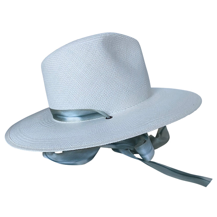 The Bexley white toquilla straw wide-brim hat with blue-grey silk drop-down ribbon, left-side product cutout