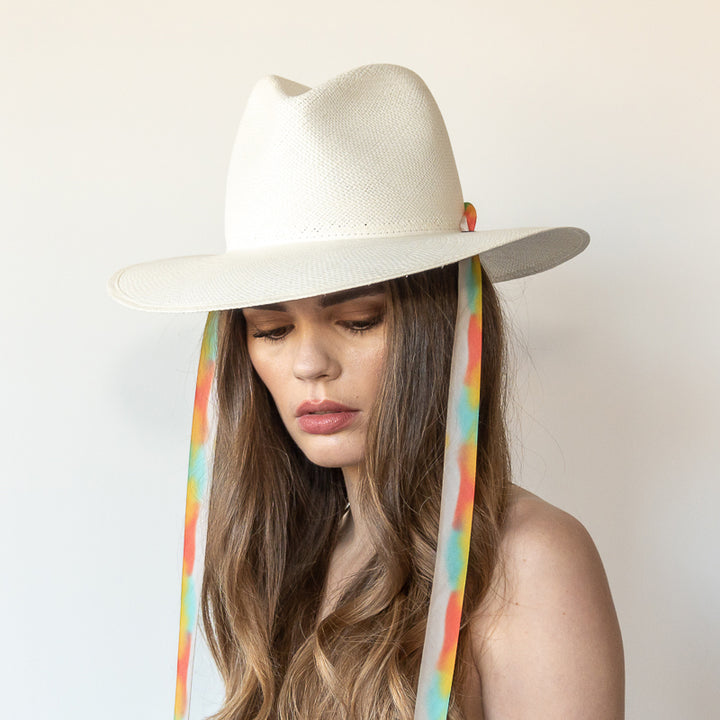 Khia Tullae The Billie white toquilla straw wide-brim hat with multicolor pastel rainbow drop-down silk ribbon ties, side view on model