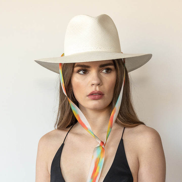 Khia Tullae The Billie white toquilla straw wide-brim hat with multicolor pastel rainbow drop-down silk ribbon tied under chin, front view on model