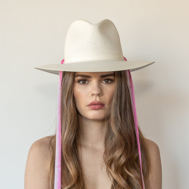 Khia Tullae The Brynn white toquilla straw wide-brim hat with pink and white drop-down silk ribbon ties, front view on model