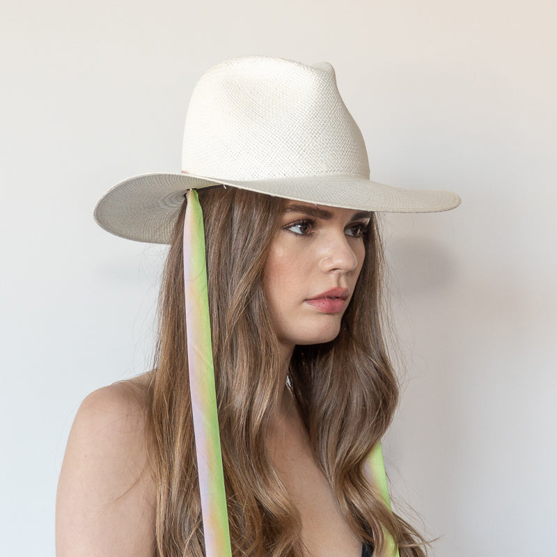 Khia Tullae The Harlow white toquilla straw wide-brim hat with neon green and pastel pink drop-down silk ribbon ties, side view on model