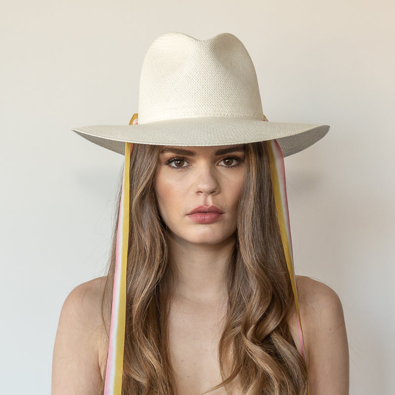 Khia Tullae The Margaux white toquilla straw wide-brim hat with golden caramel and pastel pink drop-down silk ribbon ties, front view on model