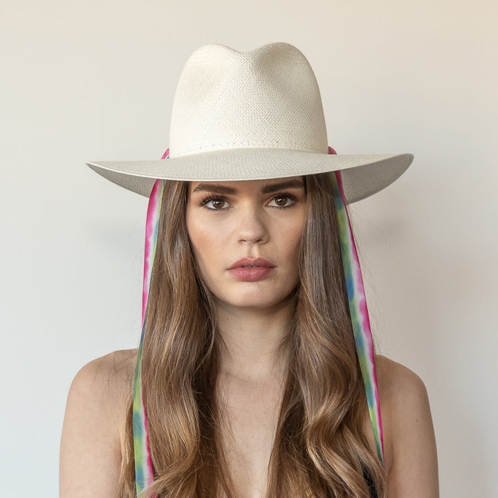 Khia Tullae The Maya white toquilla straw wide-brim hat with magenta, blue and green drop-down silk ribbon ties, front view on model