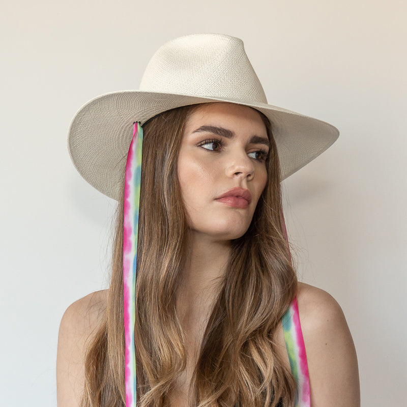 Khia Tullae The Maya white toquilla straw wide-brim hat with magenta, blue and green drop-down silk ribbon ties, side view on model