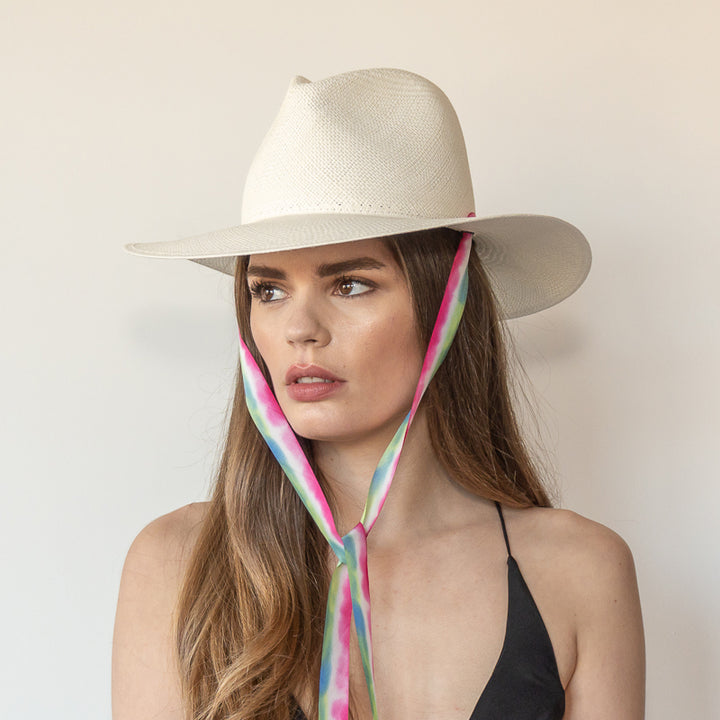 Khia Tullae The Maya white toquilla straw wide-brim hat with magenta, blue and green drop-down silk ribbon tied under chin, side view on model