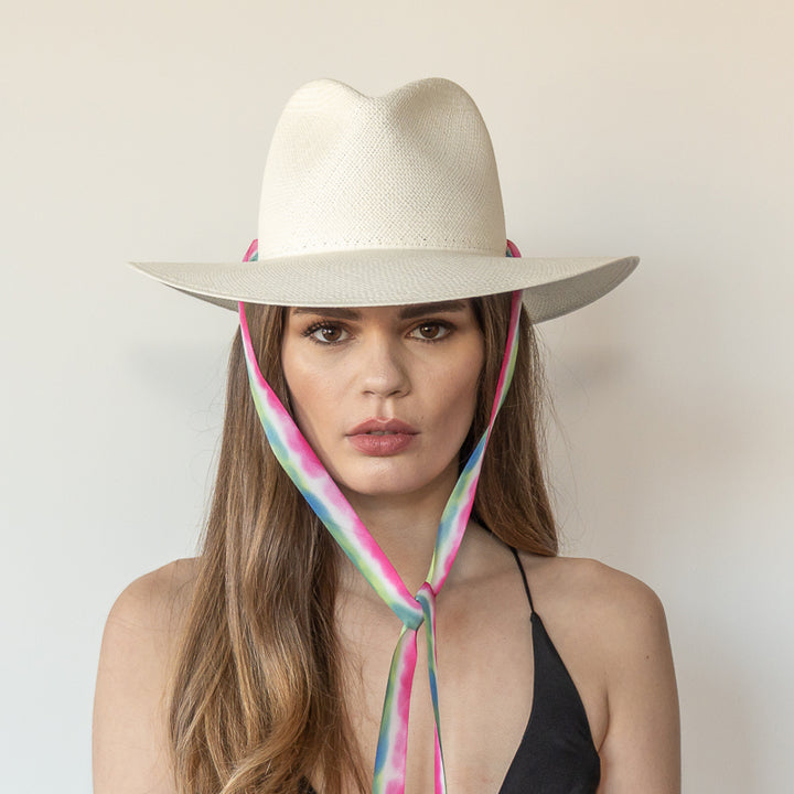 Khia Tullae The Maya white toquilla straw wide-brim hat with magenta, blue and green drop-down silk ribbon tied under chin, front view on model