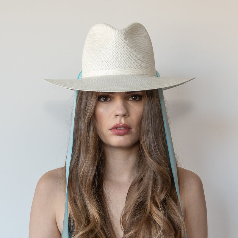 Khia Tullae The Montana white toquilla straw wide-brim hat with pastel blue and white drop-down silk ribbon ties, front view on model