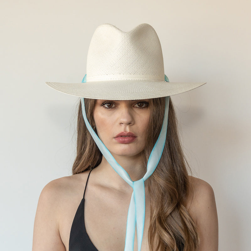 Khia Tullae The Montana white toquilla straw wide-brim hat with pastel blue and white drop-down silk ribbon tied under chin, front view on model
