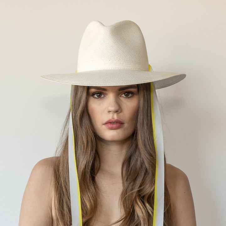 Khia Tullae The Siena white toquilla straw wide-brim hat with yellow and white drop-down silk ribbon ties, front view on model